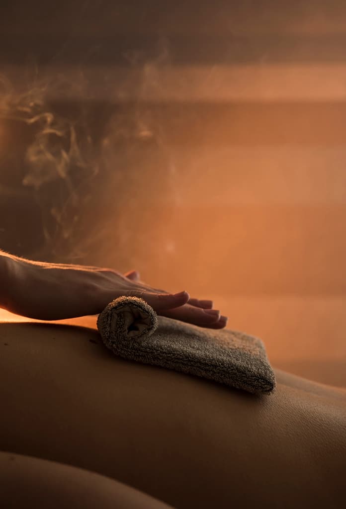 A massage therapist using a hot towel